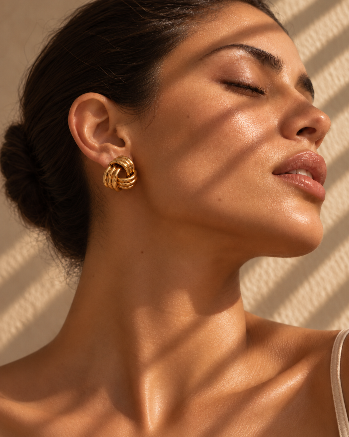 Woman in warm sunlight wearing an Ilayya gold knot earring